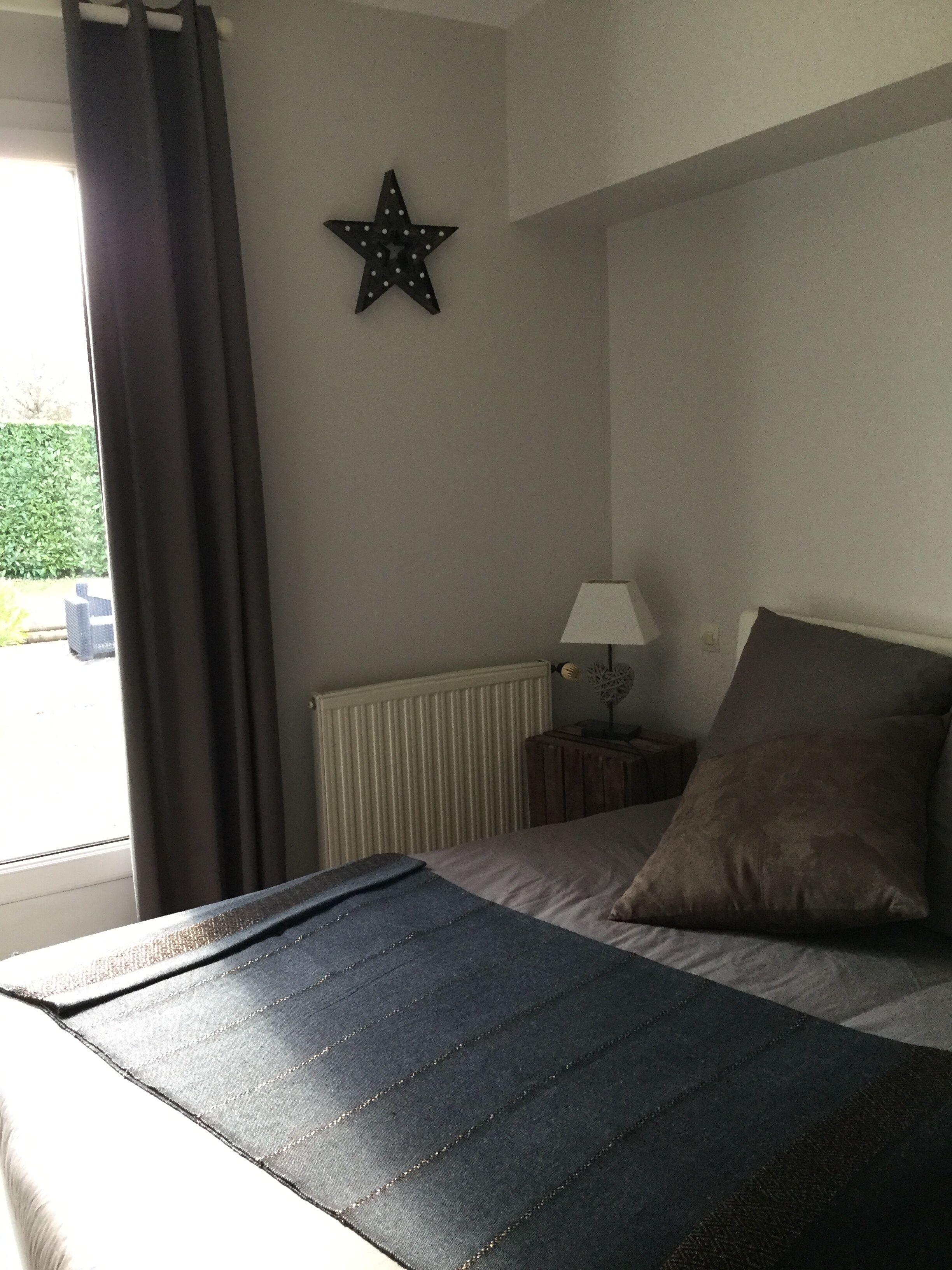 Un dormitorio con una cama, una decoración de estrella en la pared, una lámpara y una ventana con cortinas.