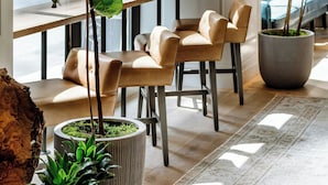 A modern interior with a dining area, large potted plants, and a seating arrangement. - Woodlark Hotel Portland, a Tribute Portfolio Hotel (Portland)