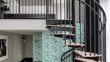 A modern interior with a spiral staircase, a loft bedroom, and a patterned wall.