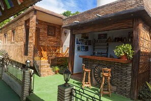 A rustic building with a bar area, wooden chairs, and a green artificial lawn. - Hostal Doña Cristina de Anita y Manel (Trinidad)