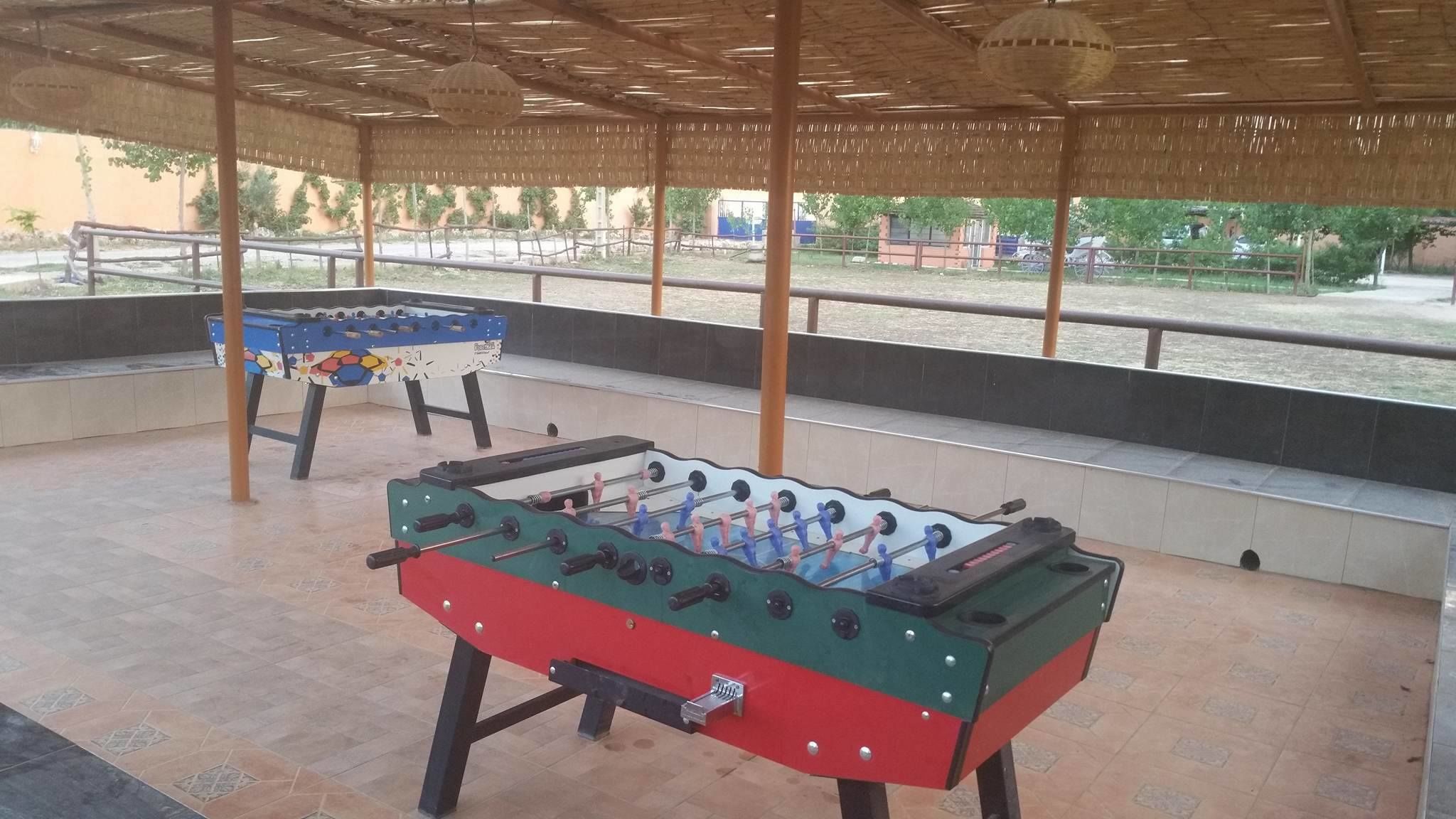 An outdoor area with two foosball tables under a covered structure.