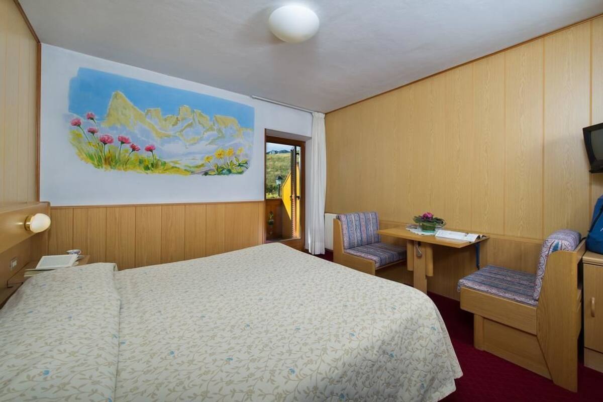 Une chambre d’hôtel avec un grand lit, un bureau avec une chaise, une télévision et un tableau au mur.
