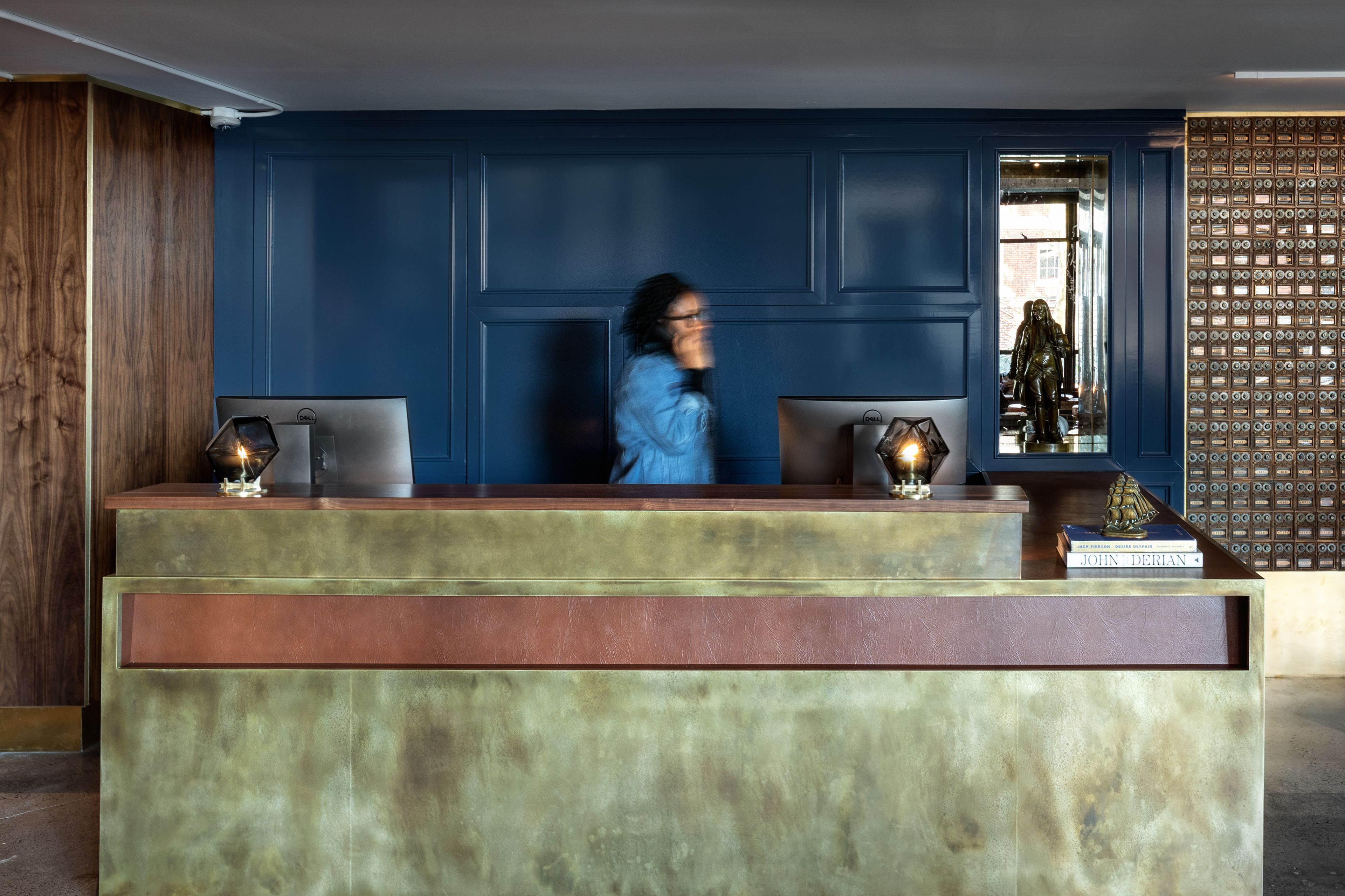 Een receptiebalie met een blauwe wand en houten lambrisering.