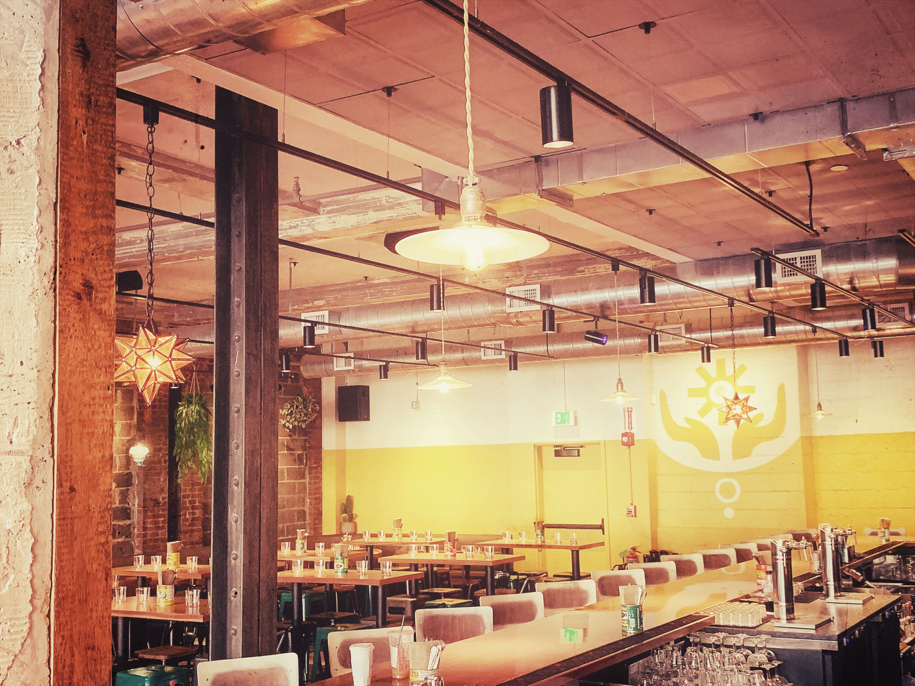 A spacious restaurant with high ceilings, exposed ductwork, and a variety of seating arrangements including tables and booths.