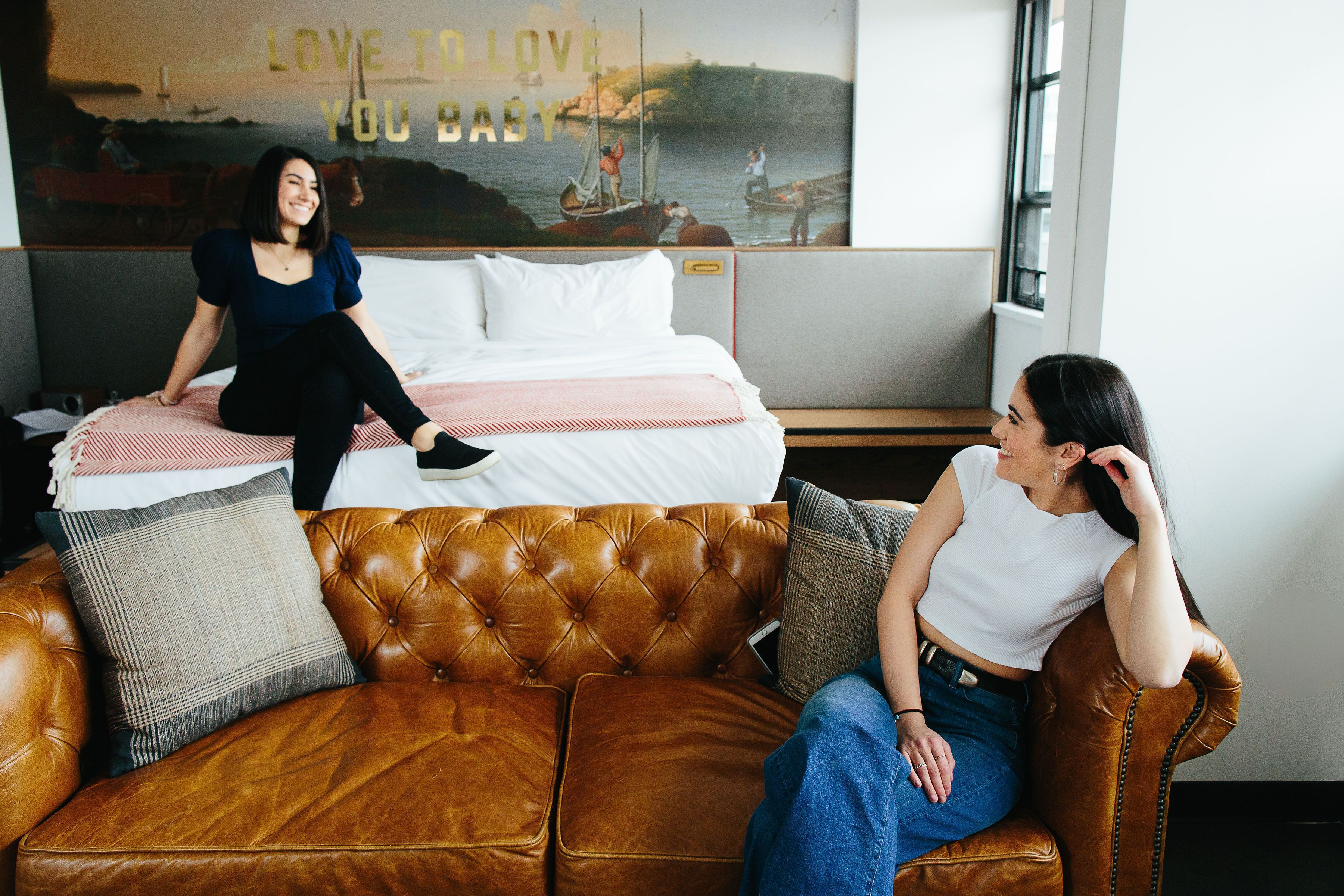 A room with a bed, a brown leather couch, and a wall with a poster.