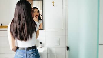 Un baño con lavamanos blanco, un espejo y un perchero para toallas.