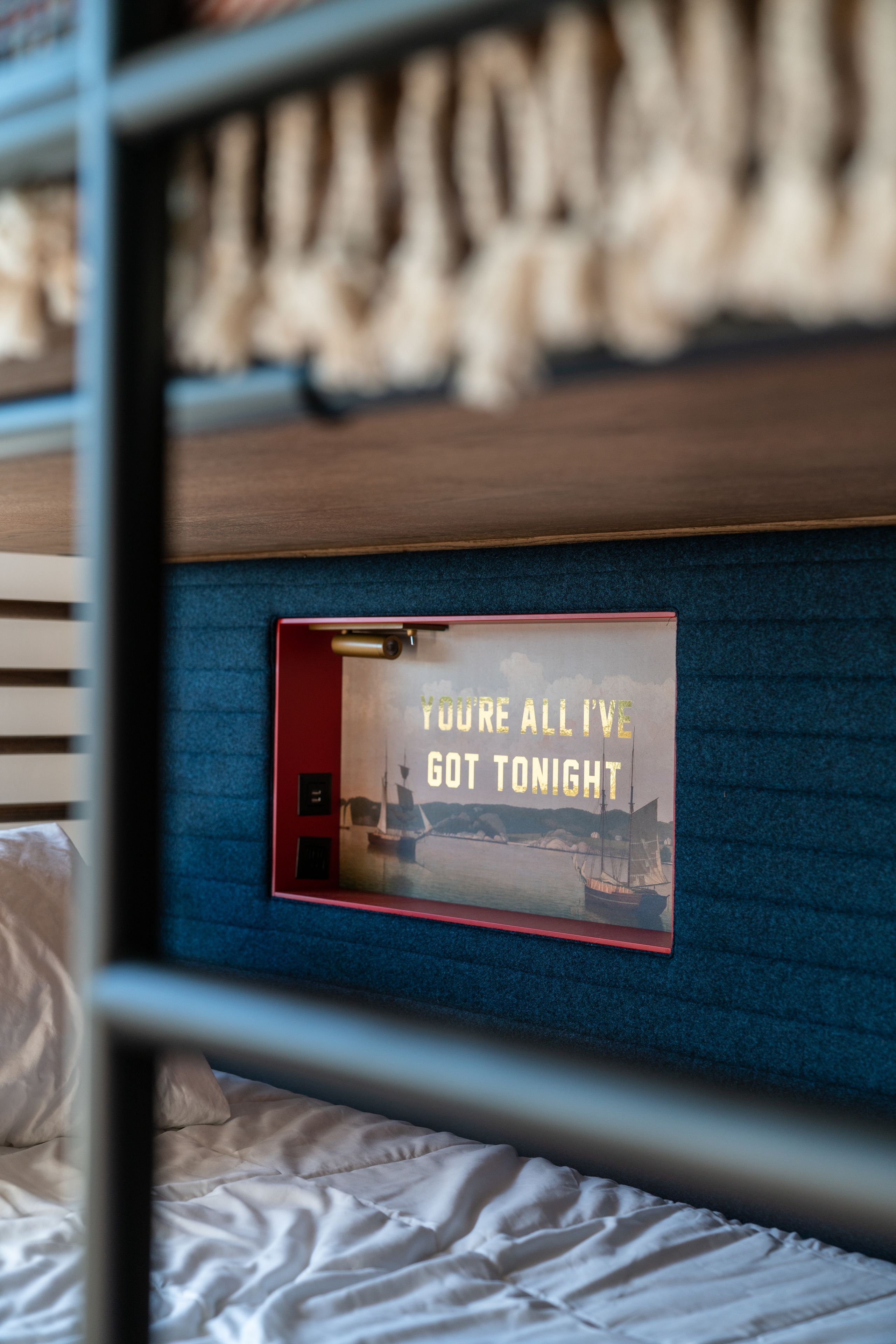 A bed with a headboard that has a framed picture and the text "YOU'RE ALL I'VE GOT TONIGHT".