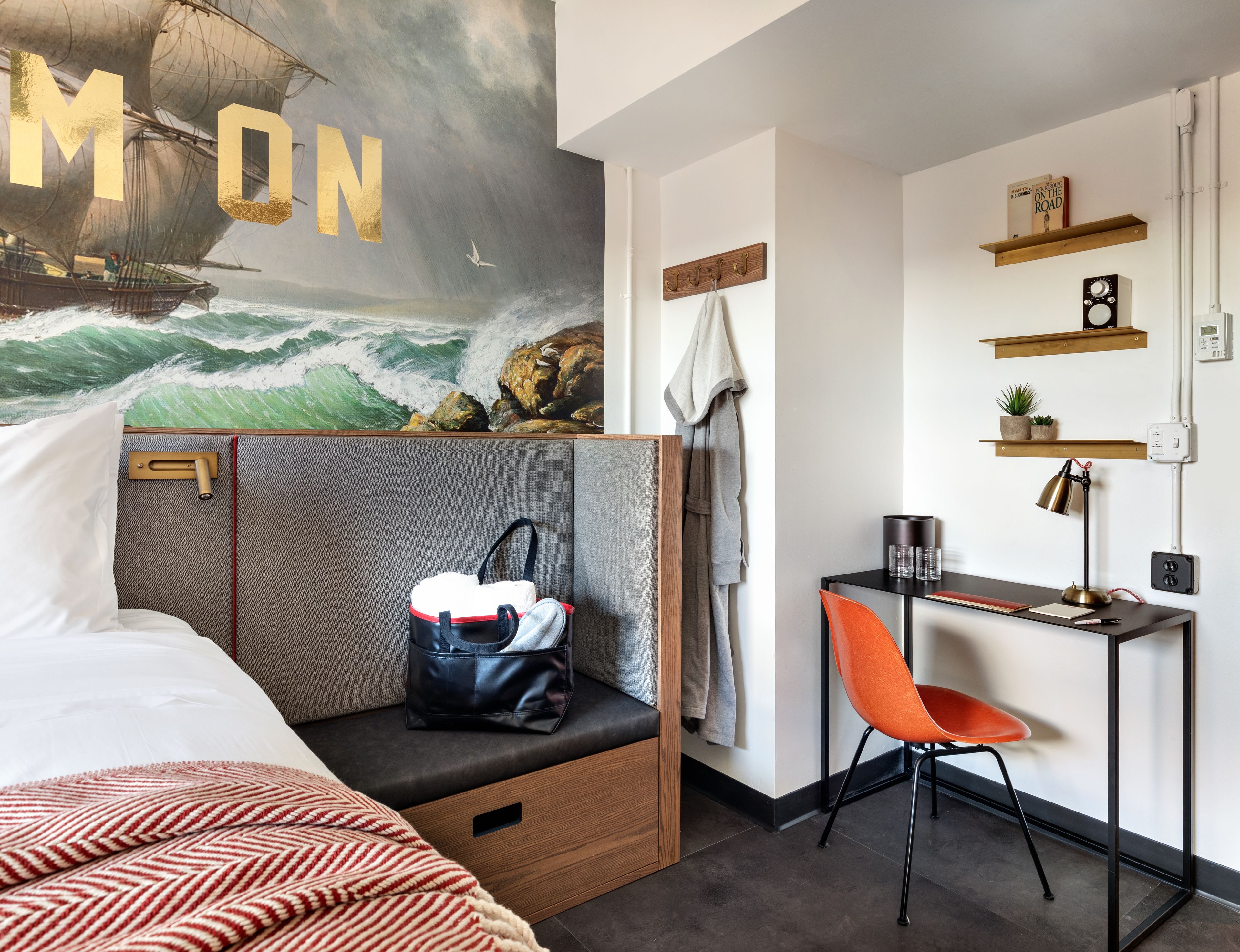 Una moderna camera d'albergo con un letto, una scrivania con una sedia, una mensola a parete e un grande murale.