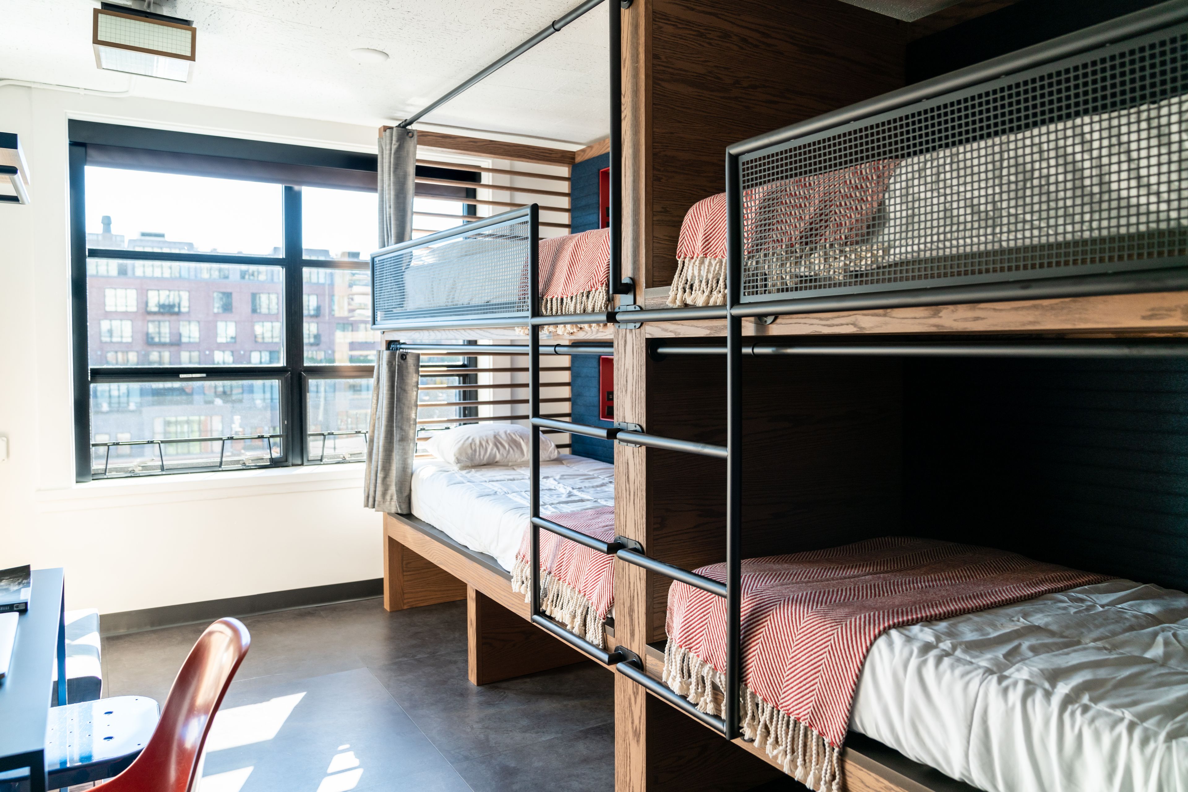 A bunk bed room with a city view, a desk, and a chair.