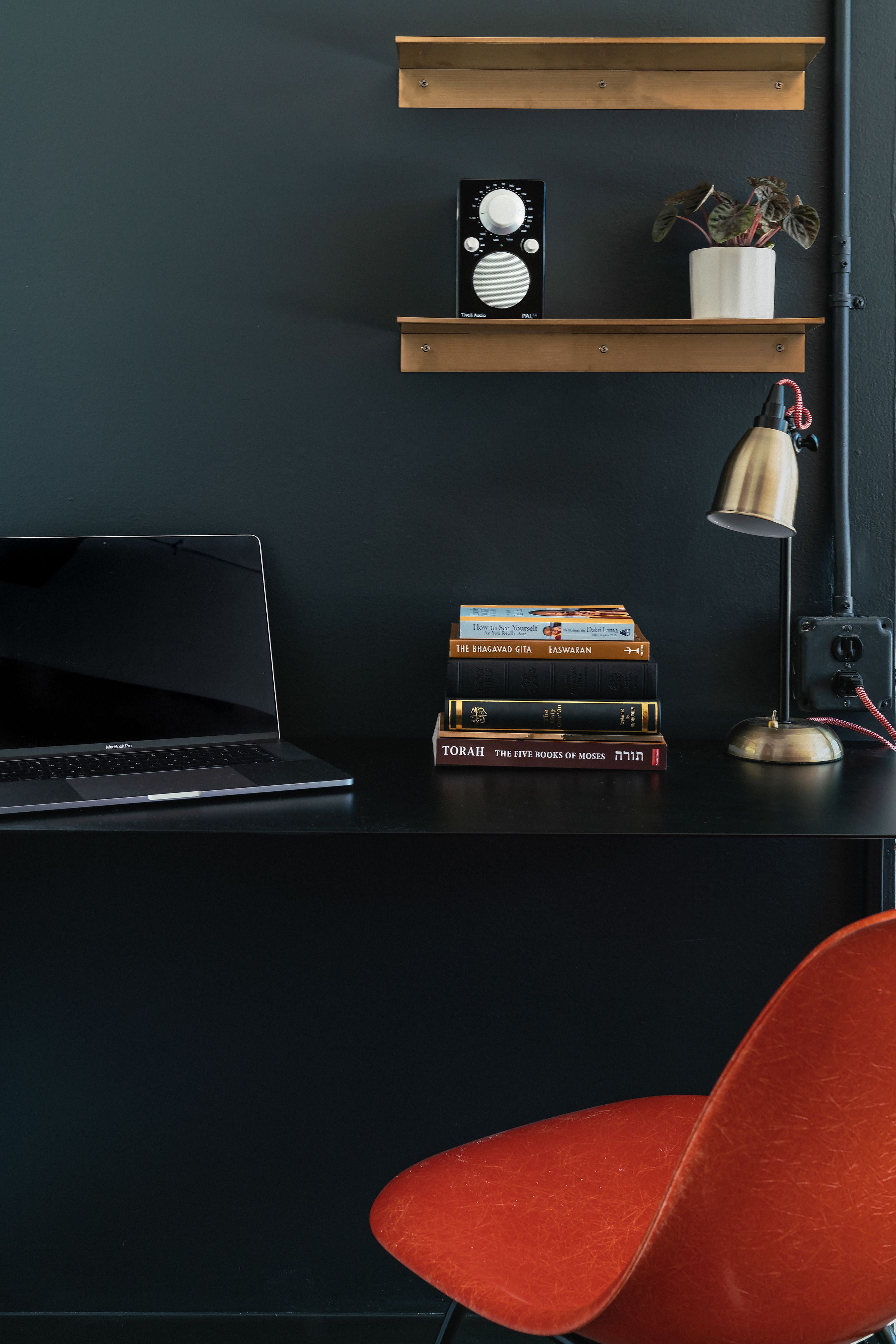 A desk with a laptop, books, a radio, and a lamp.