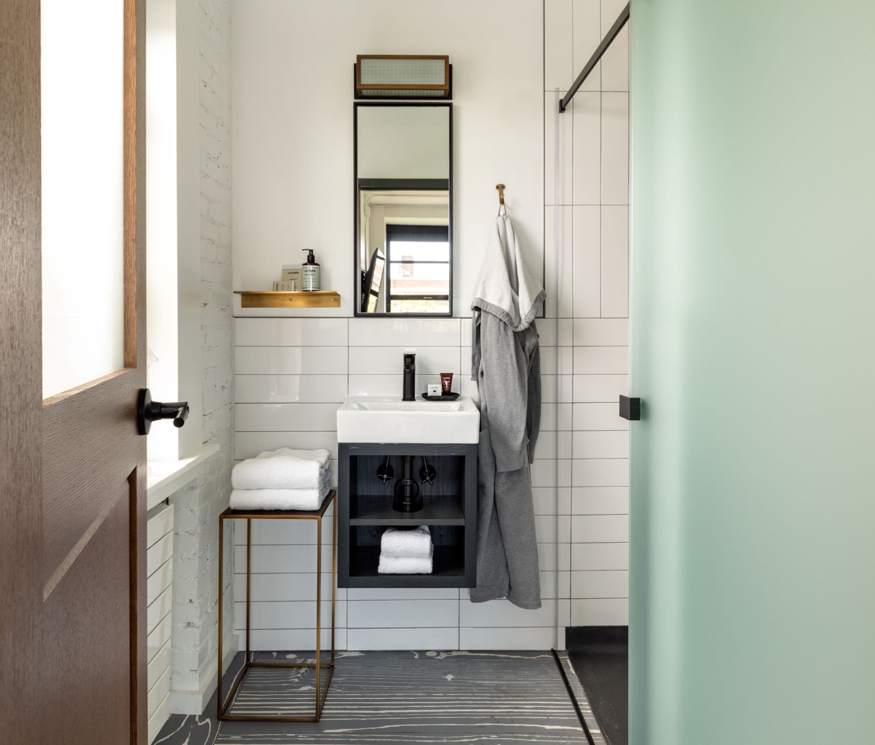 A bathroom with a white sink, a mirror, a towel rack, and a shower area.