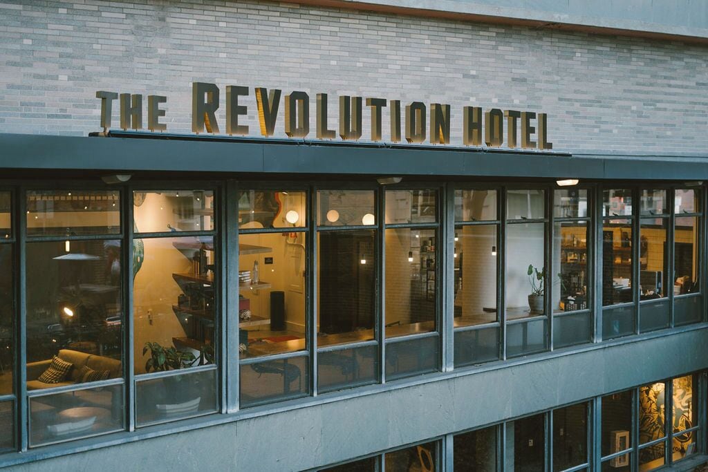 Exterior del hotel The Revolution con amplias ventanas y fachada de ladrillo.