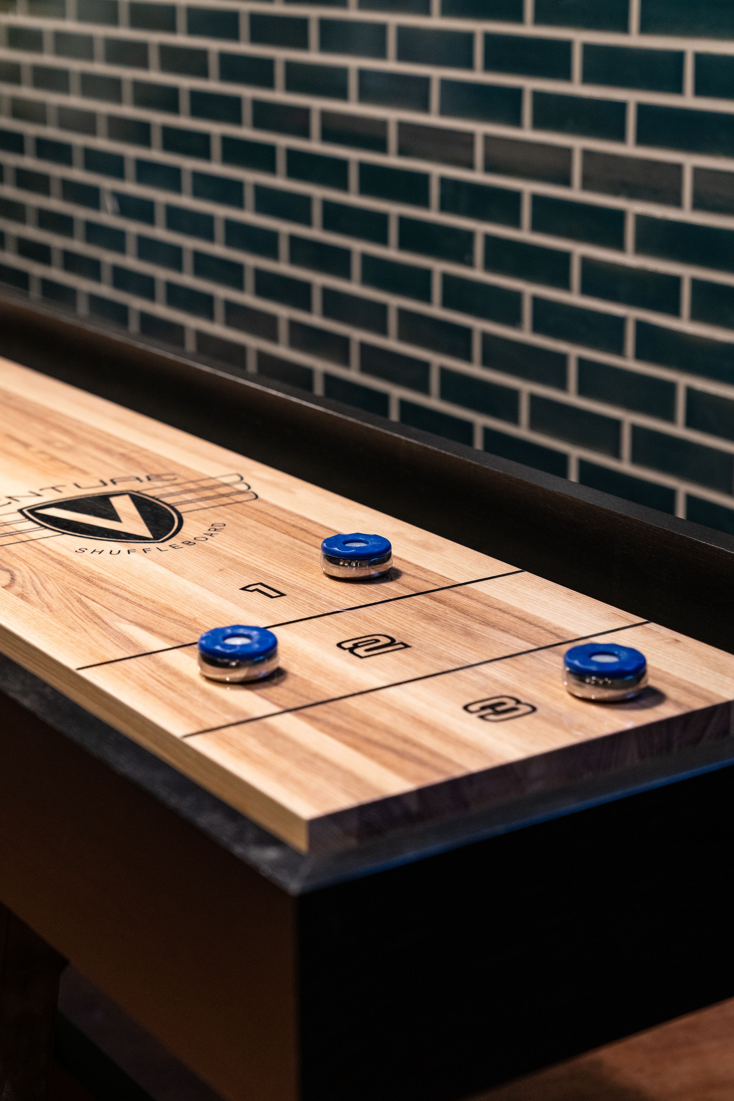 Uma mesa de jogo de shuffleboard com áreas de pontuação numeradas e um logotipo.