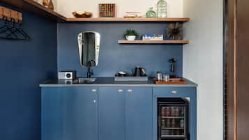 A compact kitchen with blue cabinets, a built-in sink, and a small refrigerator.