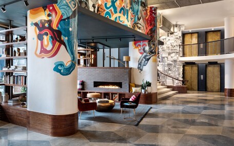 A spacious lobby with a fireplace, bookshelves, and a checkered floor.