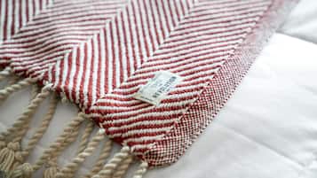 A close-up of a red and white striped macrame pillow with a tag.