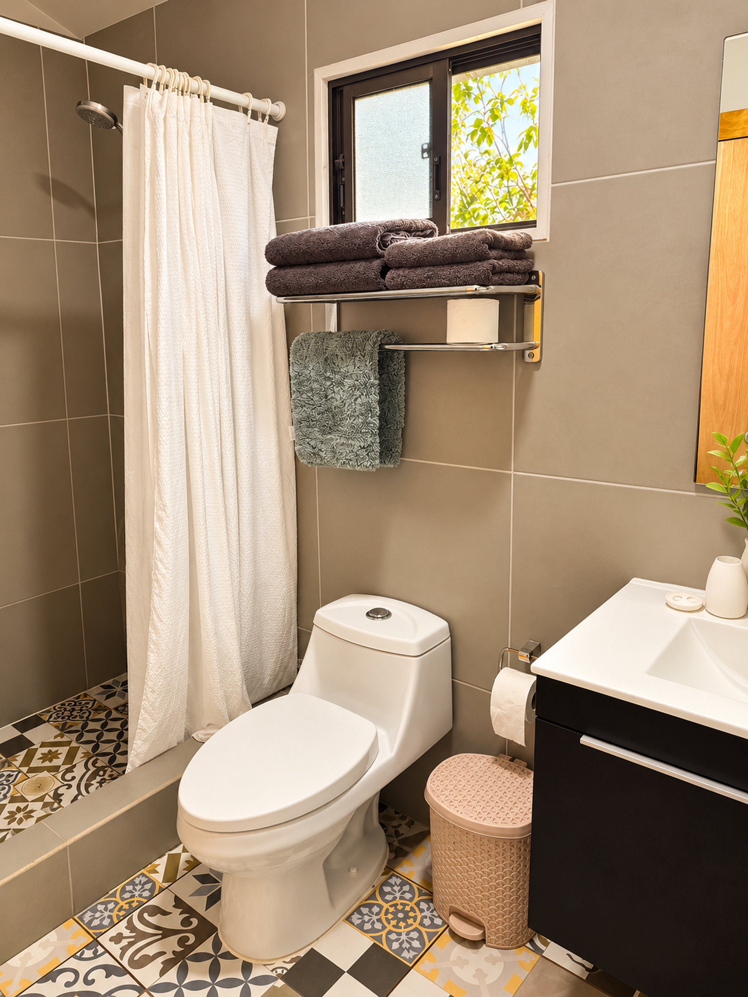 A bathroom with a toilet, shower, and sink.
