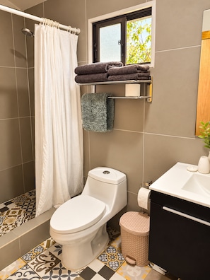 A bathroom with a toilet, shower, and sink. - Cabañas Raupa (Hanga Roa)