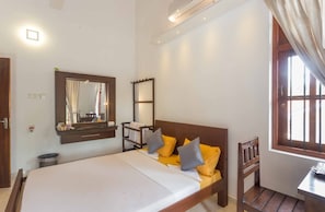 Un dormitorio con cama, espejo, mesita de noche y ventana con cortinas.
