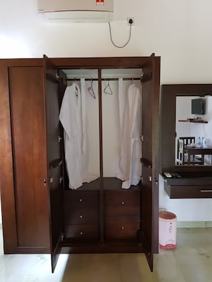 Una habitación con un armario de madera, una mesita con un hervidor y un televisor montado en la pared.