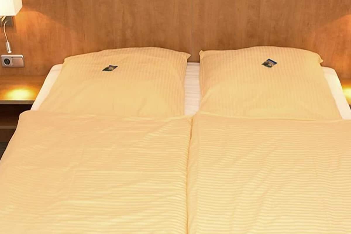 Un lit double avec une couvre-lit à rayures, deux tables de chevet avec des lampes et une tête de lit en bois.