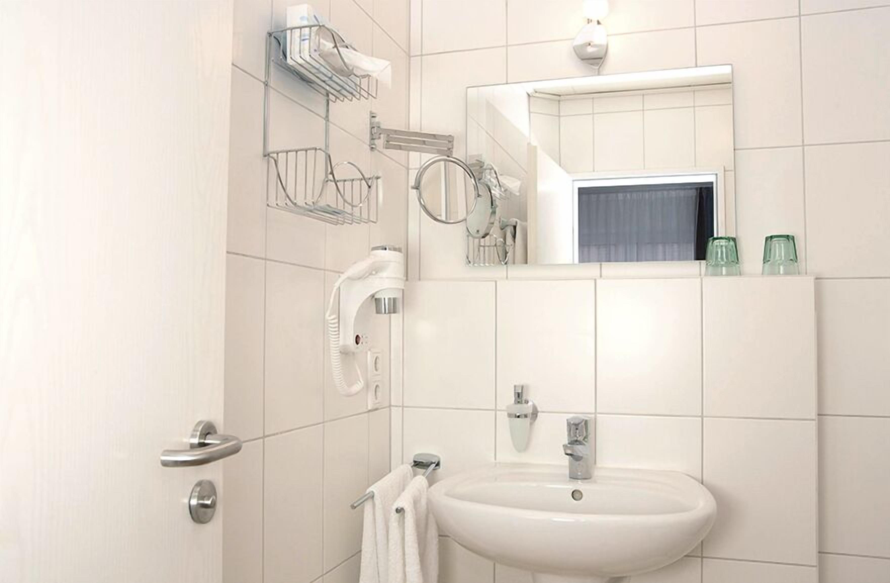 Een moderne badkamer met een wit wastafel, spiegel en handdoekhouder.