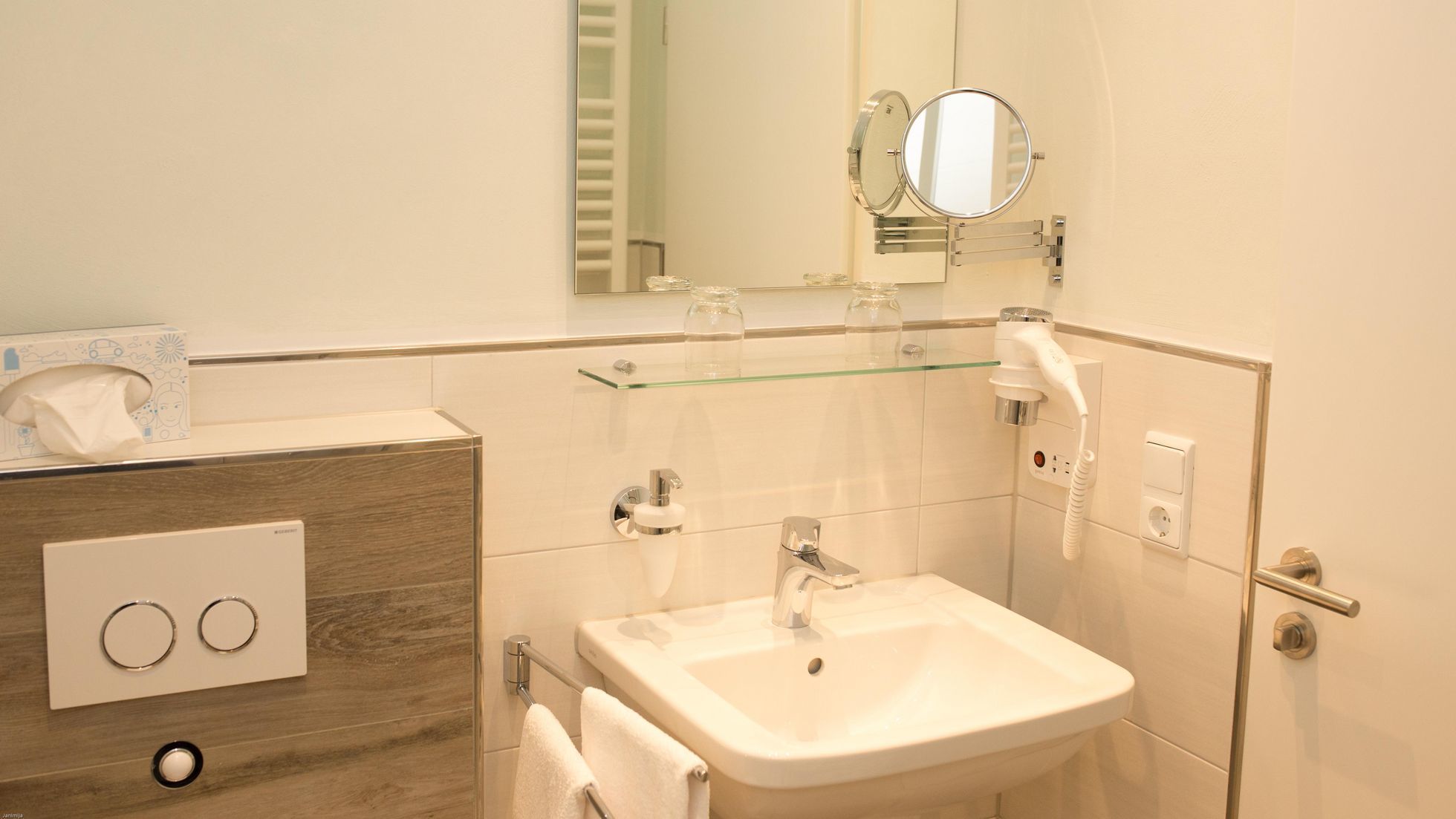 Un baño moderno con cabina de ducha de vidrio, un lavabo blanco y un espejo sobre él.