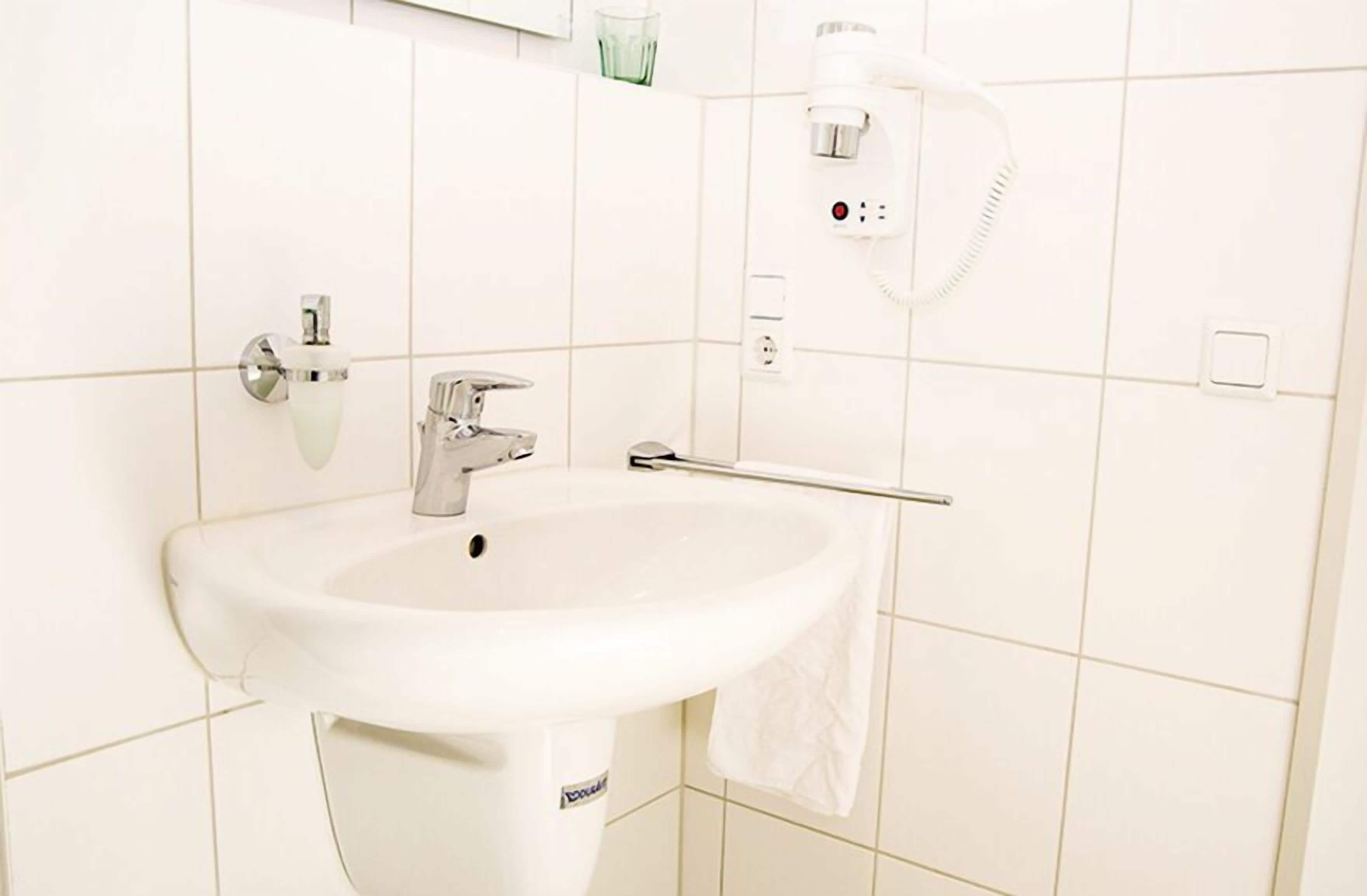 A bathroom with a white sink, a mirror, and a towel rack.