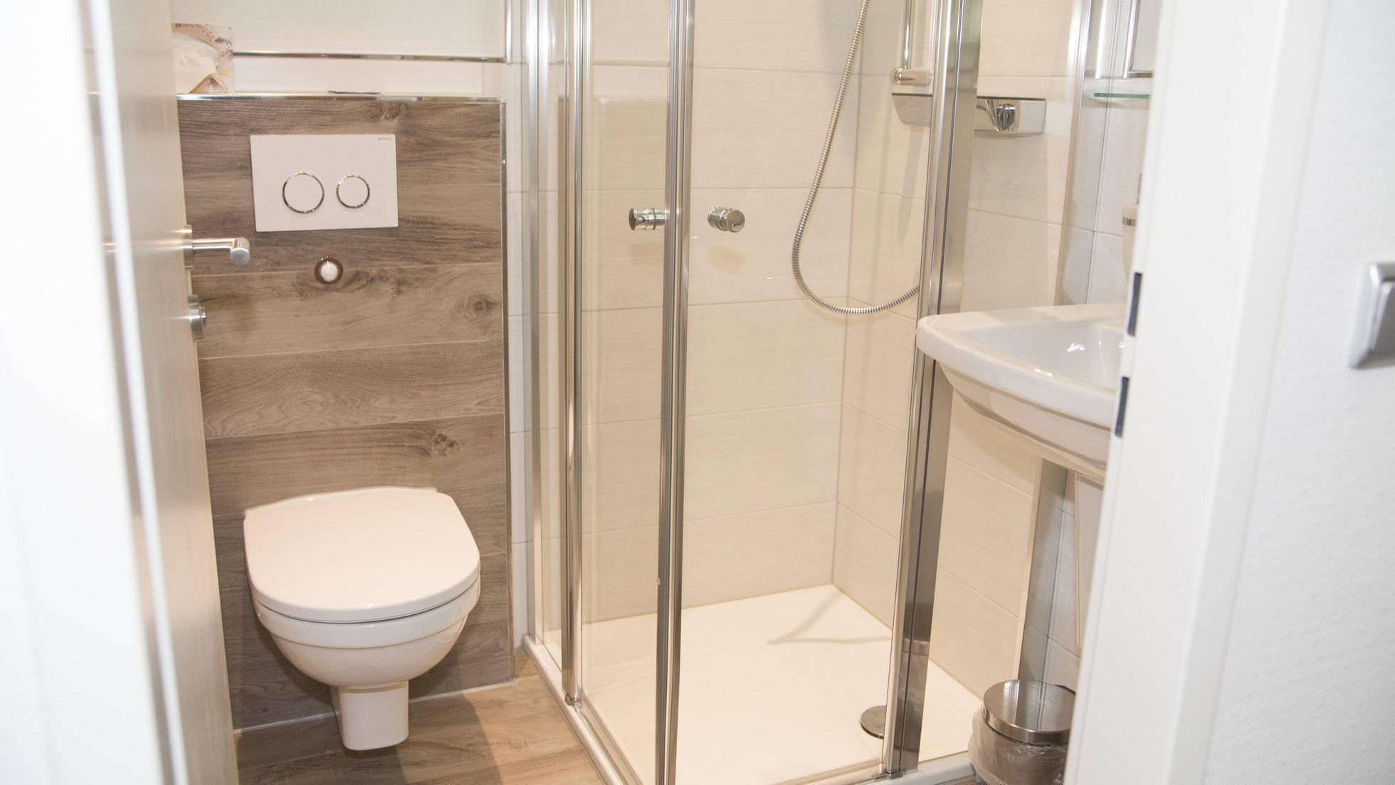 Un baño moderno con inodoro, cabina de ducha de vidrio y lavamanos.
