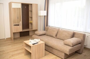 Una sala moderna con un sofá color beige, una mesa de centro de madera y un armario con espejo.