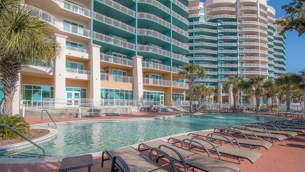 A hotel with a pool area, including lounge chairs and a pool.