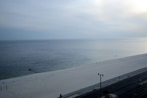 A beach with a road parallel to the shore, street lamps, and a clear view of the sea. - Sienna-Sienna 904 (Gulfport)