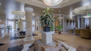 Un hall d’entrée spacieux avec une colonne centrale, des plantes en pot et un espace salon.