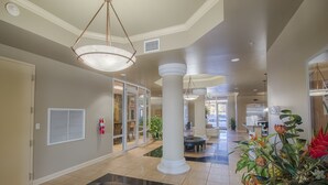 A spacious lobby with a black leather sofa, a large potted plant, and a fire extinguisher on the wall. - Sienna-Sienna 907 - Near Gulfport Beach (Gulfport)