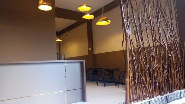 A reception area with a counter, hanging pendant lights, and a decorative branch wall. - Pondok Backpacker City Square (Malang)