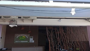 A building with a sign reading "CITY SQUARE" and a motorcycle parked in front. - Pondok Backpacker City Square (Malang)