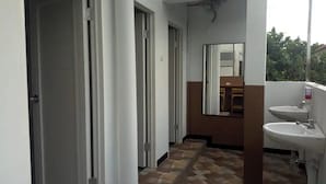 A narrow hallway with a tiled floor leading to a bathroom with two sinks and a mirror. - Pondok Backpacker City Square (Malang)