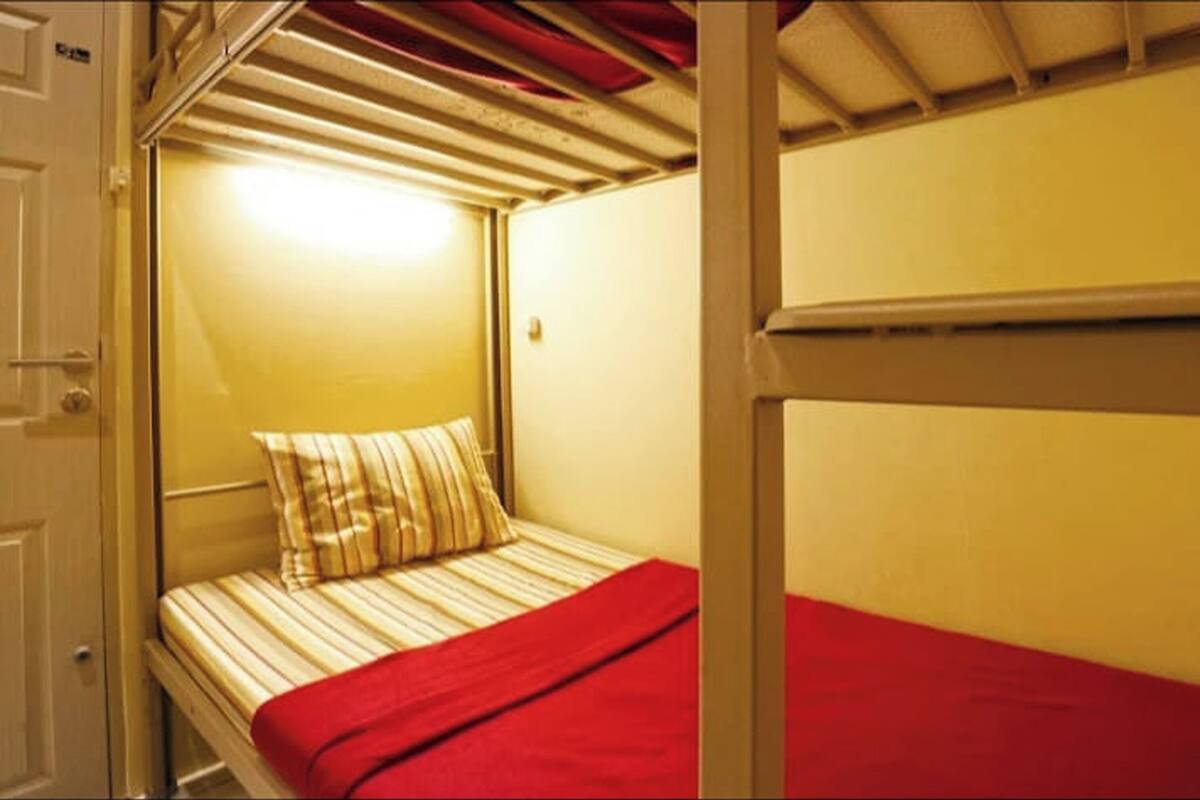 A bunk bed with a red blanket and striped pillow.