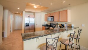 A kitchen with a central island, bar stools, and modern appliances. - Sienna-Sienna 303 - Near Gulfport Beach (Gulfport)