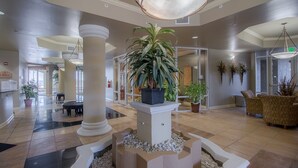 A spacious lobby with a central column, potted plants, and a seating area. - Sienna-Sienna 1201 Penthouse (Gulfport)