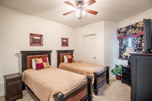 A bedroom with two beds, a ceiling fan, a door, a television, and a decorative tapestry. - Sea Breeze-Sea Breeze 410 Deluxe (Biloxi)