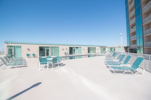 A rooftop pool area with multiple lounge chairs and a building with large windows. - Sea Breeze-Sea Breeze 410 Deluxe (Biloxi)
