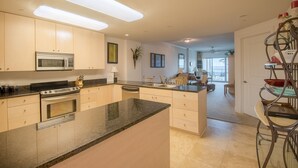 A modern kitchen with a central island, stainless steel appliances, and a view to the dining area. - Sea Breeze-Sea Breeze 410 Deluxe (Biloxi)