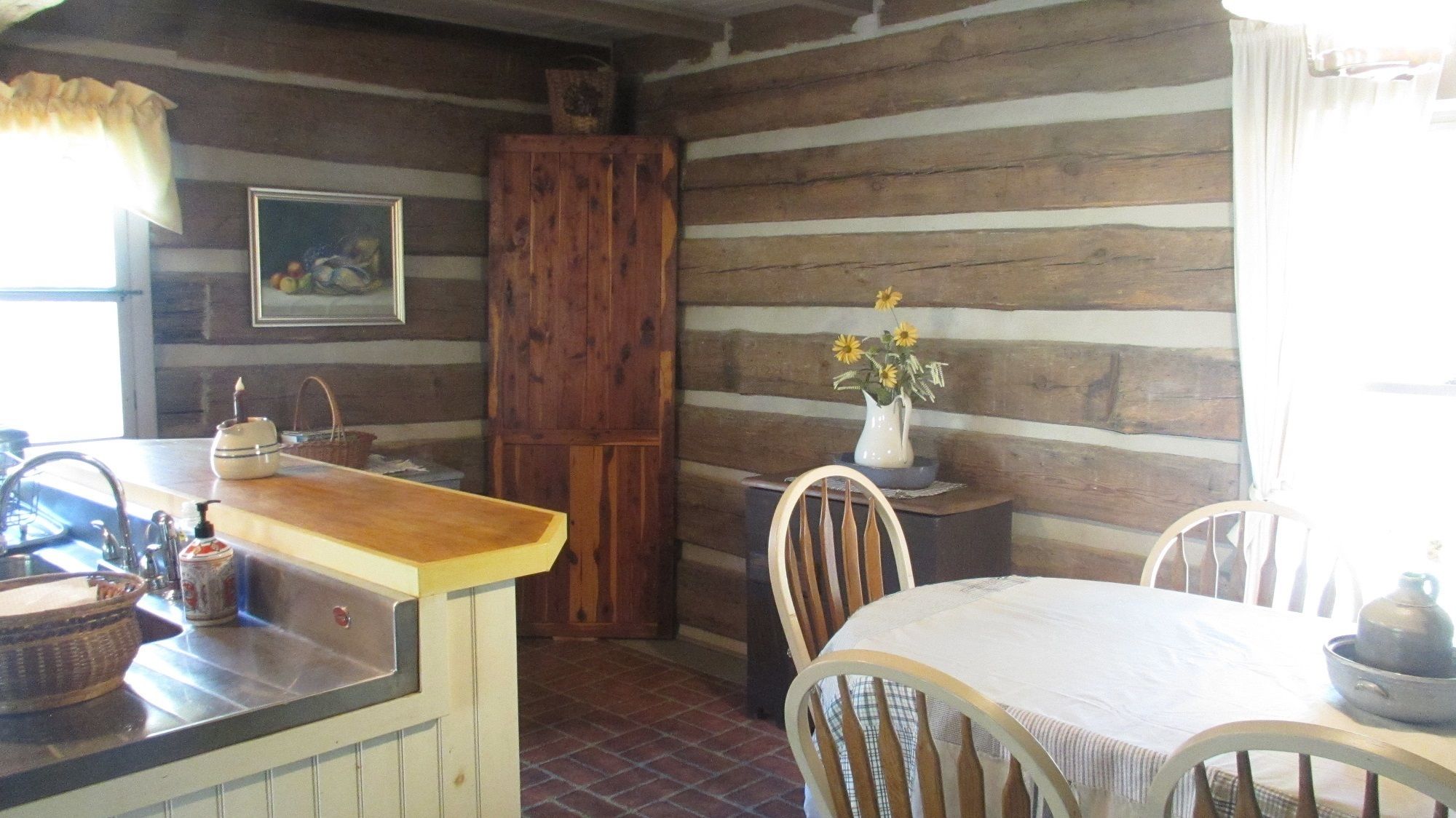 Une cuisine rustique avec des murs en bois, un comptoir en bois, un évier et une table à manger avec des chaises.