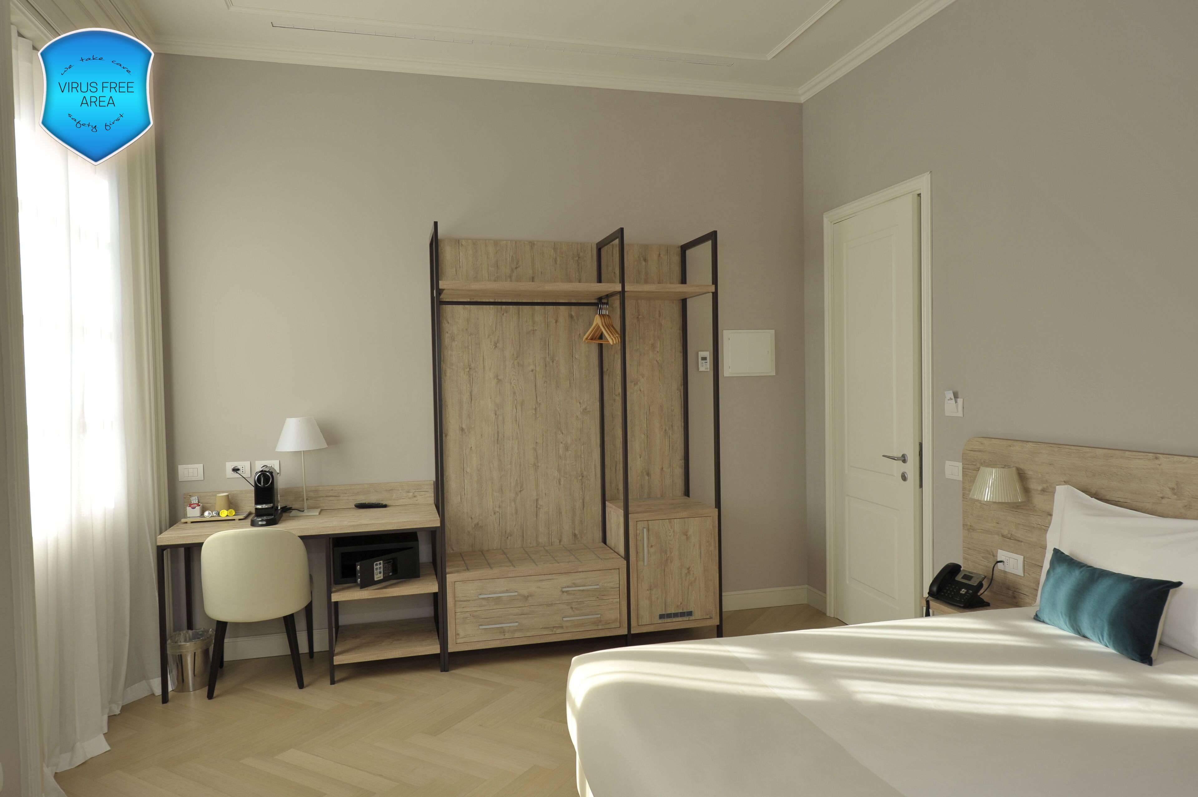 Une chambre d’hôtel comprenant un lit, un bureau avec une chaise, une armoire et une table de chevet avec une lampe.