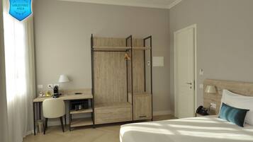Une chambre d’hôtel comprenant un lit, un bureau avec une chaise, une armoire et une table de chevet avec une lampe.