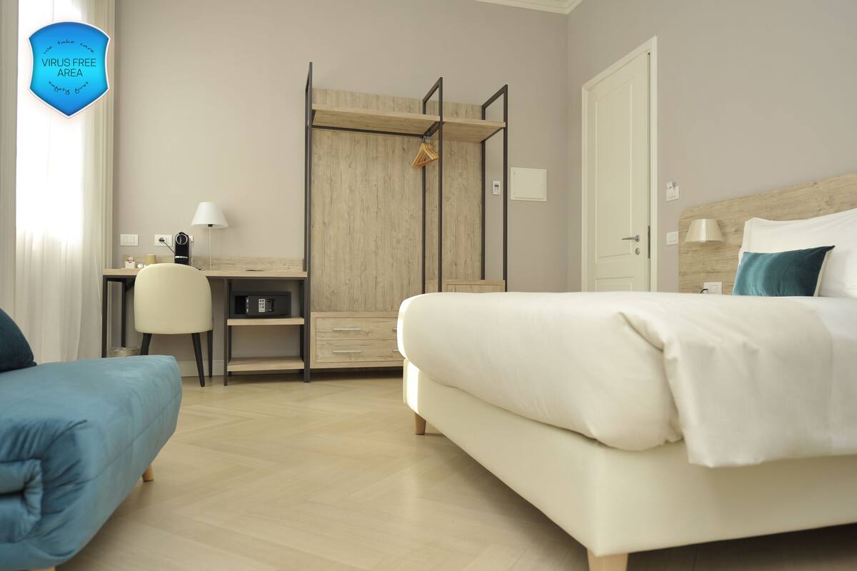 Una camera d'albergo con un letto, una scrivania, una sedia, un armadio e una lampada.