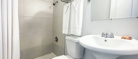 Un baño con ducha, inodoro, lavabo y toallero.