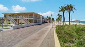 A beachfront hotel with a central staircase, palm trees, and a clear sky. - Paradise Oceanfront HBH (Hollywood)