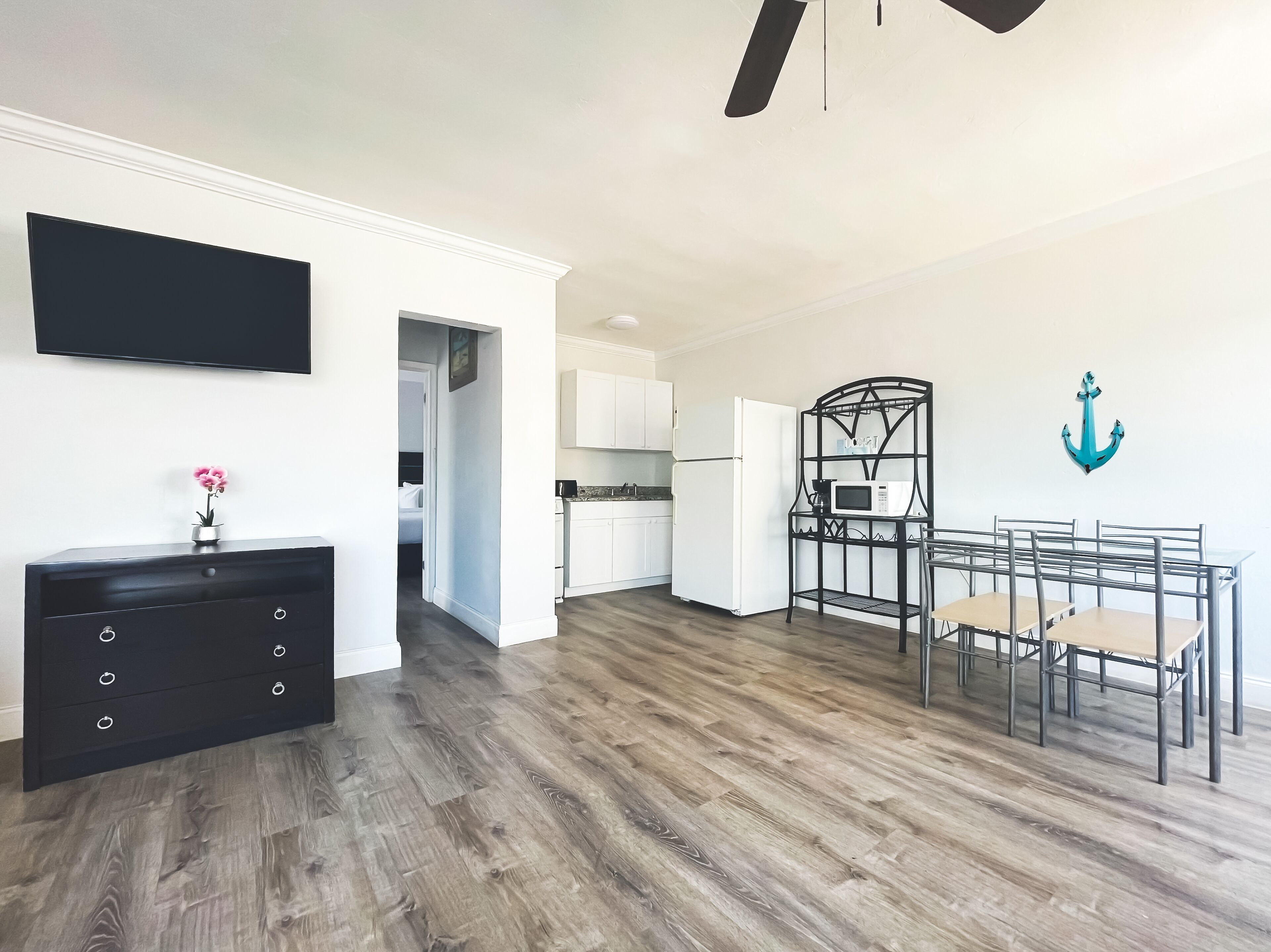 A modern kitchen with white cabinets, a black countertop, and a dining area with a metal table and chairs.